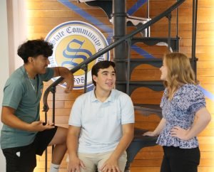 Three students talking near a staircase on campus
