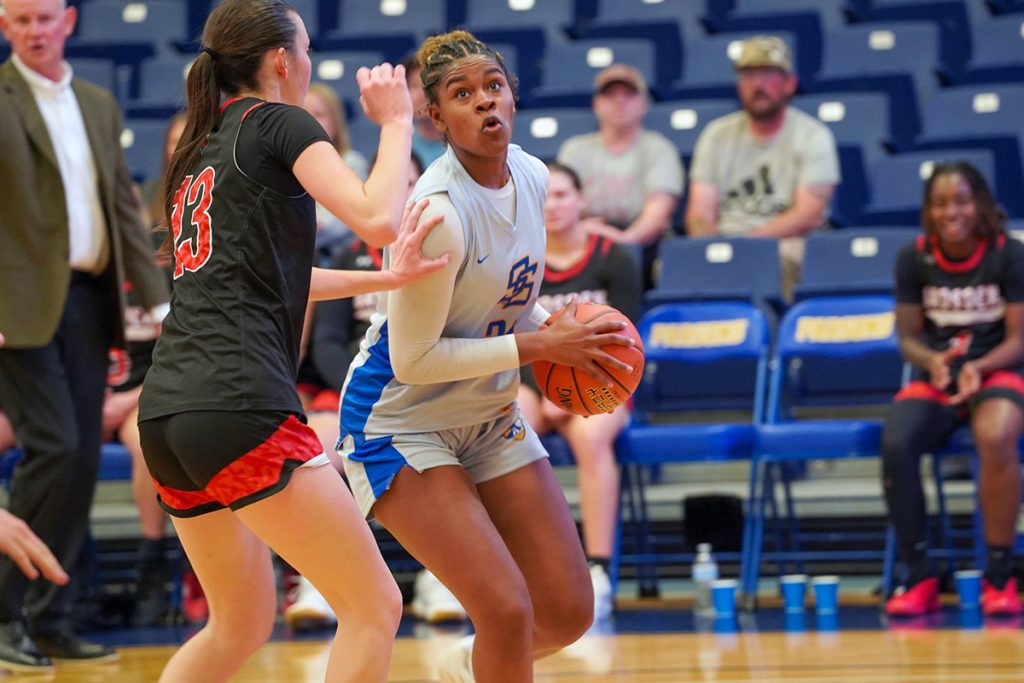 two basketball players during a game, on has the ball while the other blocks