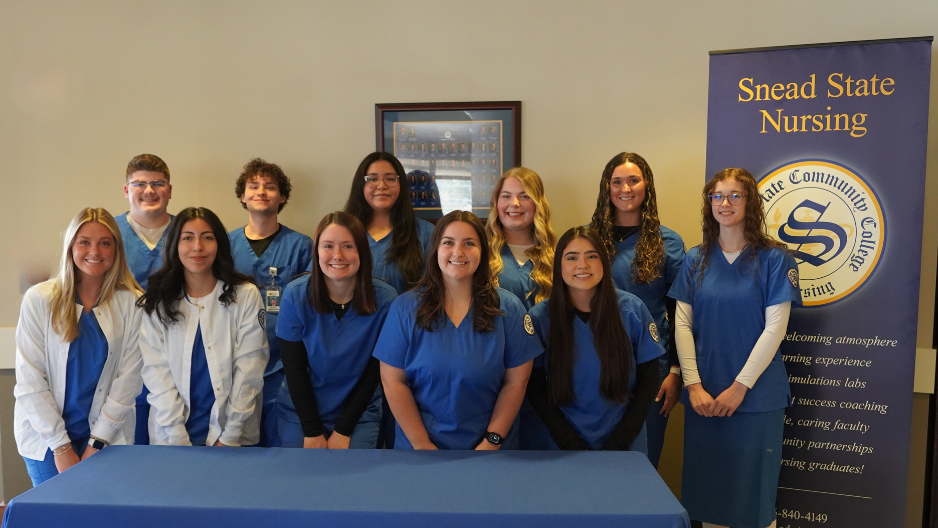 eleven nursing students posing behind a table for a group picture