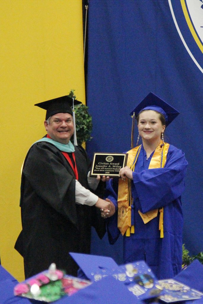 college vice president is presented an award to a graduate during the graduation ceremony