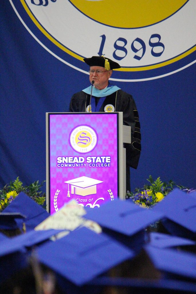 college president standing on stage during graduation in his regalia